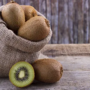 Fresh kiwi in a sack on an old wooden board Fresh kiwi in a sack on an old wooden board