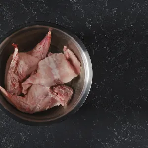 Fresh rabbit hind legs and a saddle are soaked in water with vinegar in a metal bowl Fresh rabbit hind legs and a saddle are soaked in water with vinegar in a metal bowl