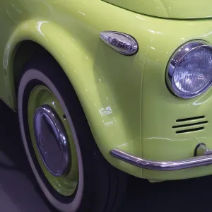 Frontal view of a light green classic car with shiny wheel