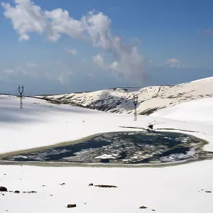 Frozen mountain lake embedded in snow-covered hills under a clear sky