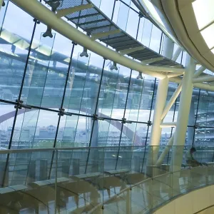Futuristic atrium environment, glass wall and metallic construction inside big public hall with sitting man