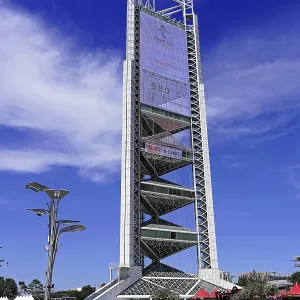 Futuristic tower stands imposing under clear blue sky in urban surroundings Futuristic tower stands imposing under clear blue sky in urban surroundings