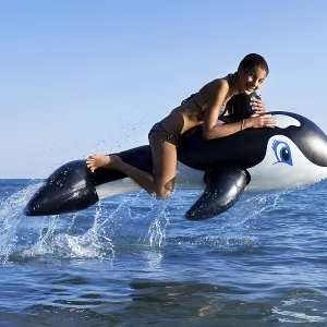 Girl sitting on inflatable orca jumping in the sea Girl sitting on inflatable orca jumping in the sea