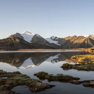 Glaciated mountain peaks reflected in a mountain lake at sunset Glaciated mountain peaks reflected in a mountain lake at sunset