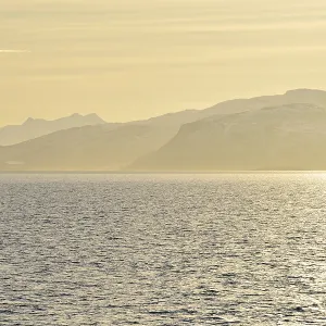 Glistening water and the mountains of Hinnoya in the yellow morning light Glistening water and the mountains of Hinnoya in the yellow morning light