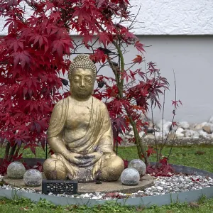 Gold-colored Buddha figure in a front garden
