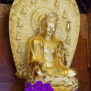 Golden Buddha with floral decoration in front of ornate wood paneling Golden Buddha with floral decoration in front of ornate wood paneling