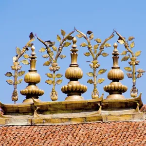 Golden Buddhist ornaments decorate a roof under a blue sky Golden Buddhist ornaments decorate a roof under a blue sky