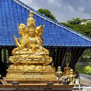Golden Buddhist statue in front of a blue roof with cloudy sky Golden Buddhist statue in front of a blue roof with cloudy sky