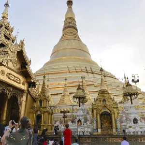 Golden pagoda with worshippers sitting in front of building