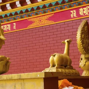 Golden statues on a red brick background with Buddhist symbols and decorations Golden statues on a red brick background with Buddhist symbols and decorations