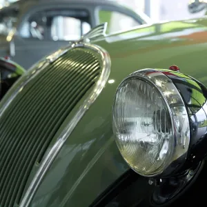 Green classic car with striking round headlights and chrome details