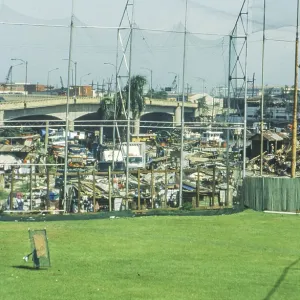 Green lawn of a sports field, slums behind it