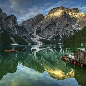 Green mountain lake with boats and boathouse