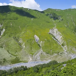 Green mountains and valleys with flowing river under blue sky Green mountains and valleys with flowing river under blue sky
