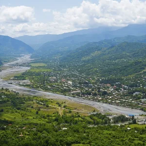 Green valley with a river course surrounded by mountains under a partly cloudy sky