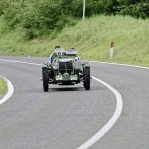 Green vintage car drives on winding country road Green vintage car drives on winding country road