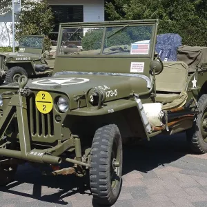 Green vintage jeep with military markings parked on a paved area
