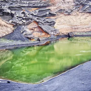 Green volcanic lake (Lago Verde) surrounded by dramatic rock formations and landscape reflections