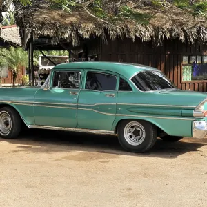 Green and white vintage car in perfect condition parked in front of a building in tropical Cuba Green and white vintage car in perfect condition parked in front of a building in tropical Cuba