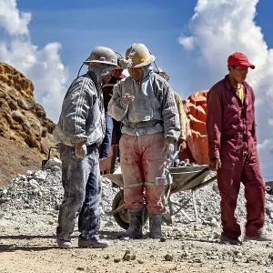 A group of miners stand and chat in a rocky landscape