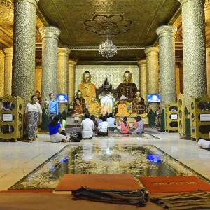 Group of people meditating in richly decorated temple room with pillars