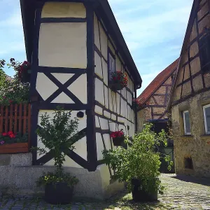 Maison à colombages avec des plantes en fleurs et des pavés historiques à Bad Wimpfen.