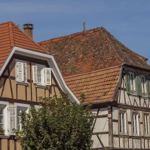 Half-timbered houses with red tile roofs and white shutters on a sunny day