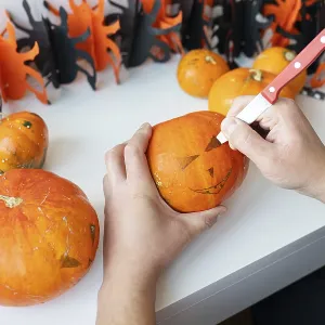 Halloween October 31st. A man cuts the face of a pumpkin with a knife Halloween October 31st. A man cuts the face of a pumpkin with a knife