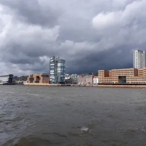Hamburg cityscape showing modern architecture and rippling Elbe river under dramatic sky