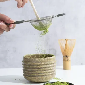 Hand sifting matcha powder through a sieve into a ceramic tea bowl during preparation Hand sifting matcha powder through a sieve into a ceramic tea bowl during preparation
