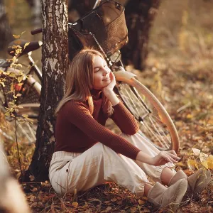Happy active young woman riding vintage bicycle in autumn park at sunset