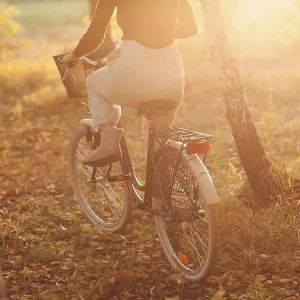 Happy active young woman riding vintage bicycle in autumn park at sunset Happy active young woman riding vintage bicycle in autumn park at sunset