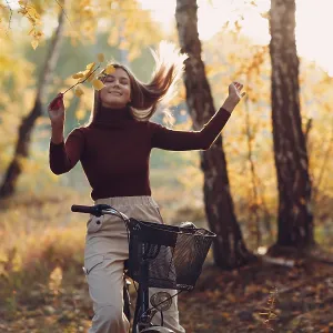 Happy active young woman riding vintage bicycle in autumn park at sunset Happy active young woman riding vintage bicycle in autumn park at sunset