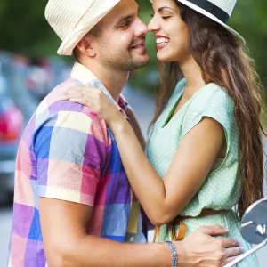 Happy young couple near the vintage scooter in the street wearing hats