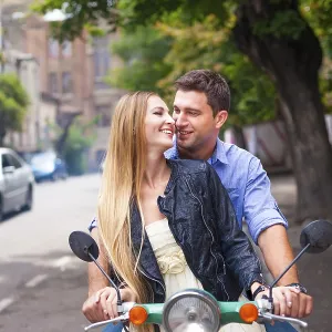 Happy young couple by a vintage scooter on the street Happy young couple by a vintage scooter on the street