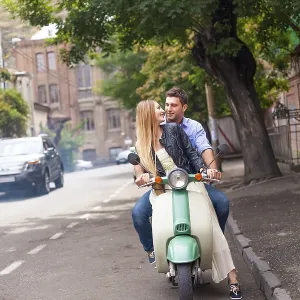 Happy young couple by a vintage scooter on the street Happy young couple by a vintage scooter on the street