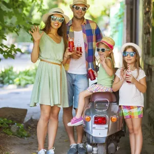 Happy young family near the vintage scooter in the street wearing hats and sunglasses Happy young family near the vintage scooter in the street wearing hats and sunglasses