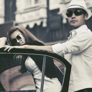 Happy young fashion couple next to vintage car