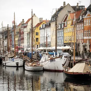 Harbor scene with boats lined up beside vibrant buildings and reflections in the water in Nyhavn Harbor scene with boats lined up beside vibrant buildings and reflections in the water in Nyhavn