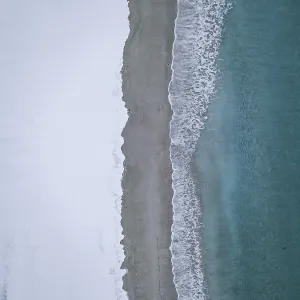 Haukland beach from above, turquoise sea water borders on snow surface