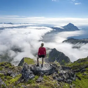 Hiker looking over mountain landscape in clouds Hiker looking over mountain landscape in clouds