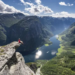 Hiker sitting on rock, view from the top of Breiskrednosi