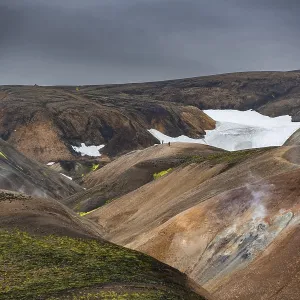 Hikers on colourful rhyolite mountains with remnants of snow