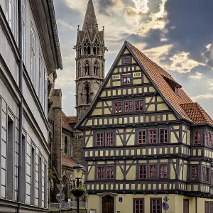Historic alley with half-timbered house and church tower Historic alley with half-timbered house and church tower