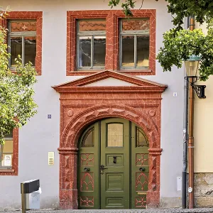 Historic building facade with green door and decorative red stone decorations Historic building facade with green door and decorative red stone decorations