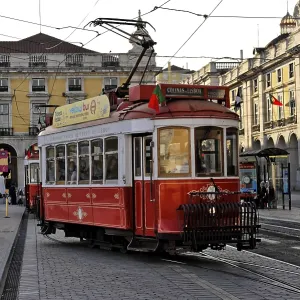 A historic red tram runs through the city center past impressive old architecture