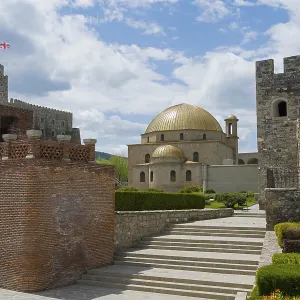 Historical building with golden dome and massive stone walls under cloudy sky
