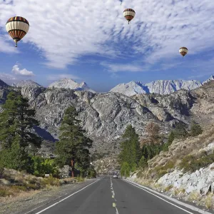 Huge balloons with the passenger basket flying over the magnificent American roads in the mountains Huge balloons with the passenger basket flying over the magnificent American roads in the mountains