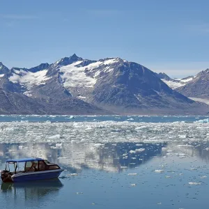 Icebergs reflected in a fjord, small blue boat